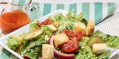 a salad with croutons, tomatoes and lettuce on a white plate