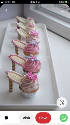 cupcakes with pink frosting and bows are lined up on a white tray