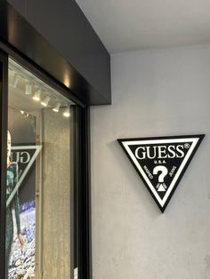 a sign on the side of a building that says guess and is next to a window