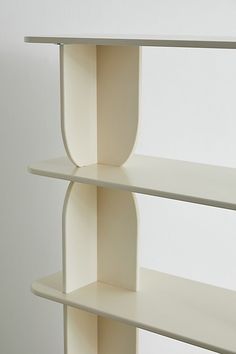 two white shelves on the wall, one with a curved shelf and another with an oval shelf