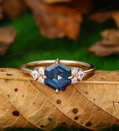 an engagement ring with a blue stone surrounded by white diamonds on top of a leaf