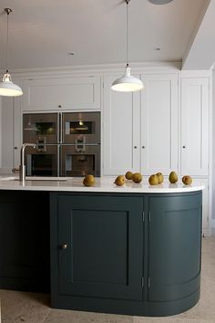 an island in the middle of a kitchen with two lights hanging from it's ceiling