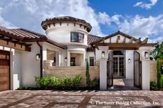 a large white house with a brown roof and gated entry way leading to the front door