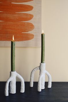 two white ceramic candlesticks sitting next to each other on top of a table