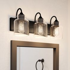 three lights on the wall above a mirror