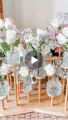 several glass vases with flowers in them on a wooden table next to a mirror