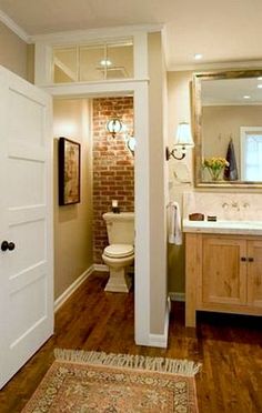 an open door leading to a bathroom with a brick wall and wood flooring on the walls