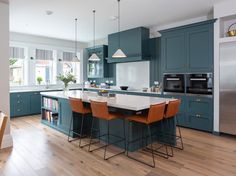 a kitchen with blue cabinets and an island in the middle, surrounded by wooden floors