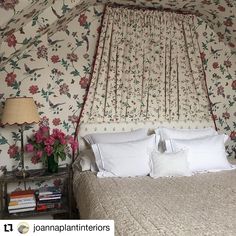 a bed in a bedroom with floral wallpaper on the walls and ceiling, next to a night stand