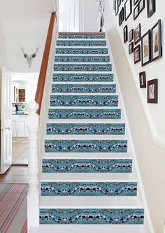 the stairs are decorated with blue and white wallpaper, along with pictures on the wall