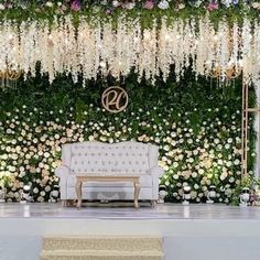 a white couch sitting in front of a lush green wall filled with flowers and greenery