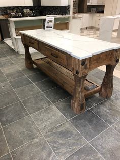 a large kitchen island made out of wood and white marble top, in the middle of an open floor plan