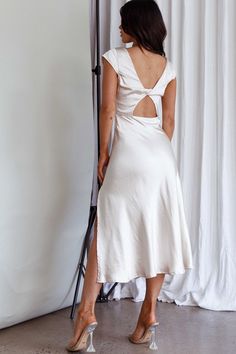 a woman standing in front of a white curtain with her back turned to the camera