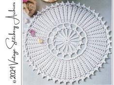 a crocheted doily is shown on a table with flowers and seashells