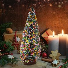 a christmas tree made out of candies and other holiday decorations next to lit candles