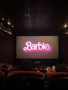 an empty theater with people sitting in seats watching the show barbie on the wall behind the screen