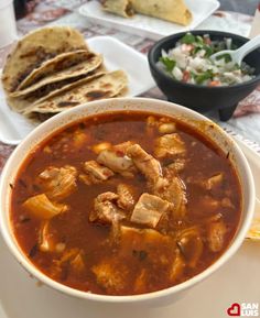 a white bowl filled with soup next to some pita bread