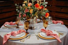 the table is set with plates, silverware and pink napkins for an elegant dinner