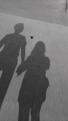 two people standing next to each other with their shadows on the ground in front of them