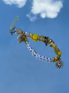 a close up of a kite flying in the sky with beads and charms on it