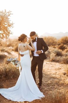 a bride and groom standing in the desert