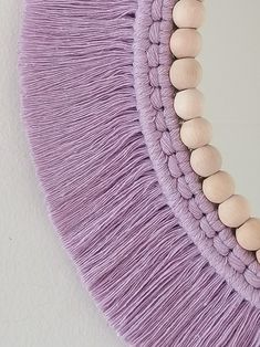 a purple purse with wooden beads hanging from it's front and back ends on a white wall