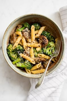 a bowl filled with pasta and broccoli on top of a white table cloth