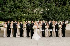 a large group of people standing next to each other in formal wear and holding bouquets