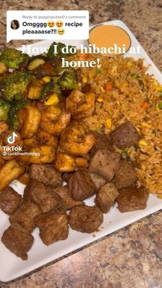 a white plate topped with meat and veggies next to rice on top of a counter