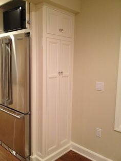 a stainless steel refrigerator freezer sitting inside of a kitchen next to a white cabinet