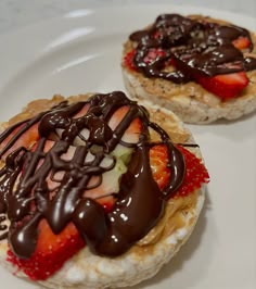 two pastries covered in chocolate and strawberries on a white plate