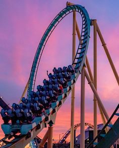 a roller coaster with people riding it at sunset