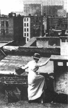 a woman standing on top of a roof with her arms outstretched in front of the camera