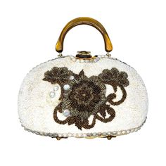 "Vintage 1950's embellished handbag by Adele has a natural woven wicker body. The front of the purse is encrusted in crème glass seed beads with a large bronze flower in the center. There is a row of large faux pearls and AB crystals along the outside. The frame and top handle are made from swirled butterscotch Lucite. It had a gold tone rolling clasp and four brass feet. Interior is gold satin with one gold foil pocket and one metal zipper pocket. Purse measures 9\" wide by 6.5' tall by 3\" acr Embellished Cream Bags For Events, Luxury Embellished Cream Bags, Luxury Beige Embellished Bags, Cream Evening Bag With Detachable Handle, Embellished Cream Evening Bag, Embellished Beige Clutch Evening Bag, Handheld Beaded Beige Evening Bag, Beige Beaded Handheld Evening Bag, Evening Beige Embellished Shoulder Bag