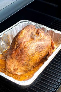 a roasting turkey in foil on an outdoor grill