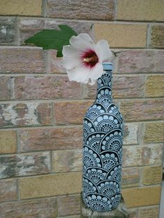 a blue and white vase with a flower in it sitting on a stone block wall