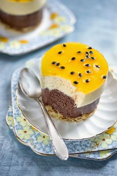 two desserts are sitting on plates with spoons next to each other and one has a yellow frosting in the middle