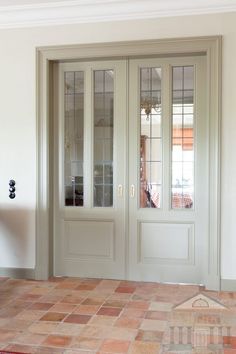 an empty room with double doors and tiled flooring in front of the glass door