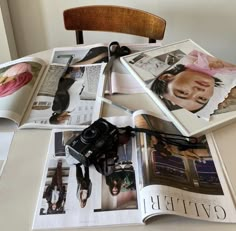 an open magazine sitting on top of a table filled with pictures and other items next to a wooden chair