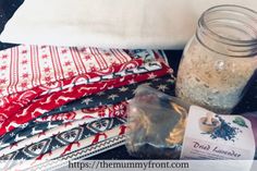 a glass jar filled with sand next to folded towels and other items on top of a table