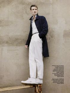 a man standing on top of a wooden bench wearing white pants and a blue jacket