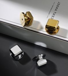 two gold and silver cufflinks sitting next to each other on top of a table