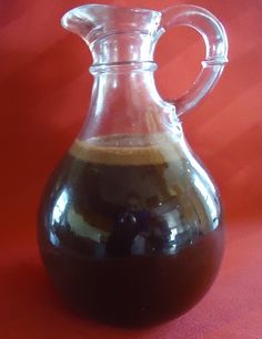 a glass pitcher filled with liquid sitting on top of a red tableclothed surface