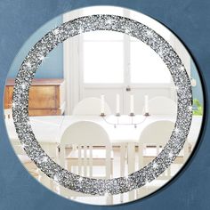 a round mirror reflecting a dining room table and chairs in the center, with silver sparkles on it