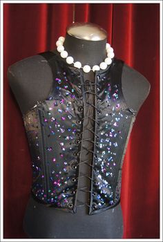 a black corset with multicolored sequins and pearls on it