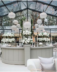 an elegant reception setup with chandeliers and white flowers on the tables in front of glass walls