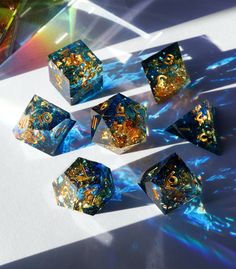 six blue and gold dice sitting on top of a white table next to a glass vase