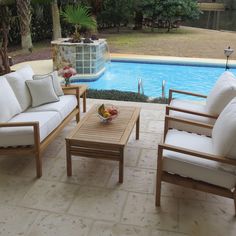 two couches and a coffee table in front of a swimming pool