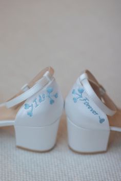 a pair of white shoes with blue flowers on them