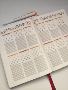 an open planner with a red ribbon around it and a calendar on the front page